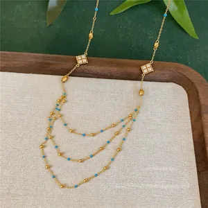 Detailed shot of multi-layer gold necklace with blue beads and zircon diamond charms