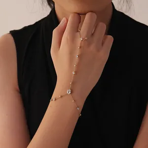 Detailed view of an elegant gold hand chain with sparkling white stones on a model.