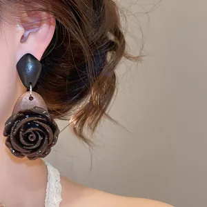 Detailed view of a vintage dark rose floral earring with niche design worn by model.
