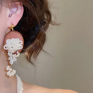 Close-up of elegant retro beaded flower tassel pearl earrings worn on a model's ear
