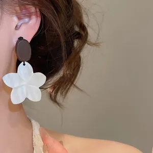 Close-up of white flower dangle earrings with oval bead on a model's ear for vintage look
