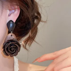 Detailed view of vintage brown resin rose drop earrings with black geometric studs