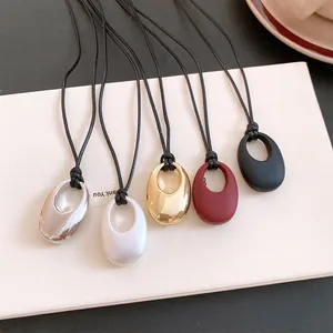 Set aus fünf minimalistischen ovalen Anhängern mit Lederbändern in verschiedenen Farben.
