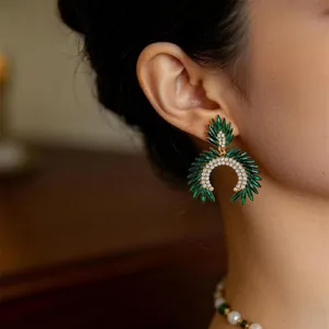 Detalle de pendientes colgantes vintage con piedras verdes marquesa y cristales brillantes.