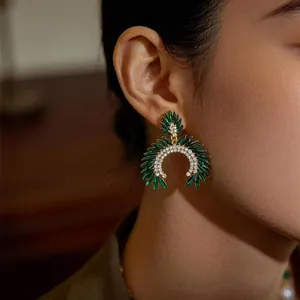Primer plano elegante de un pendiente vintage con cristales verde esmeralda en modelo