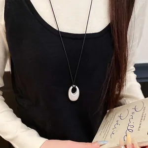 Detailaufnahme einer minimalistischen silbernen elliptischen Halskette mit Lederkordel.