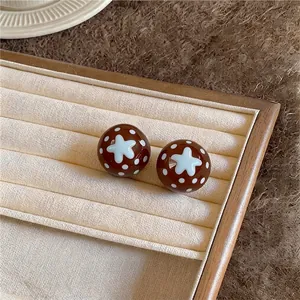 Vintage brown spherical earrings with white polka dots and star pattern in jewelry tray.