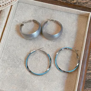 Elegante minimalistische zilveren creolen en blauwe emaille creolen op een sieradendienblad