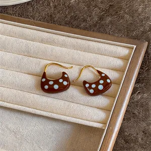 Detailed view of 18k gold plated earrings with brown enamel and white polka dots