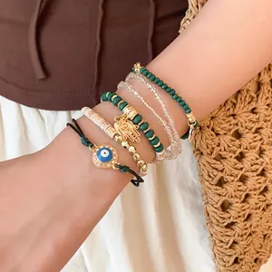 Gros plan d'un ensemble de bracelets bohèmes avec œil grec et breloques hamsa dorées