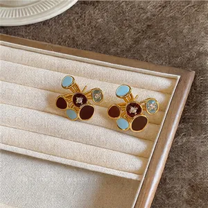 Detail view of 18k gold plated enamel earrings with light blue and brown polka dots
