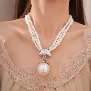 Nahaufnahme einer eleganten dreilagigen Acryl-Perlenkette mit großem Anhänger an einem Model.
