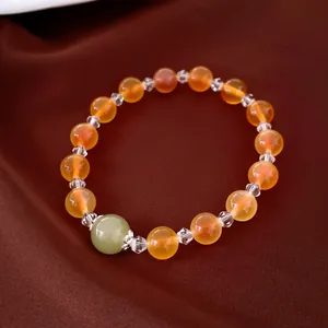 Détail d'un bracelet en perles d'agate orange avec une perle d'accent en jade sur soie