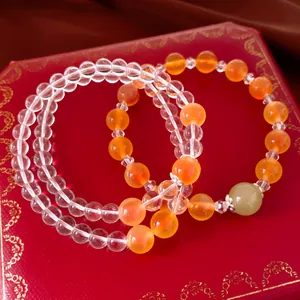 Gros plan de bracelets en agate orange et perles de cristal sur une boîte rouge.