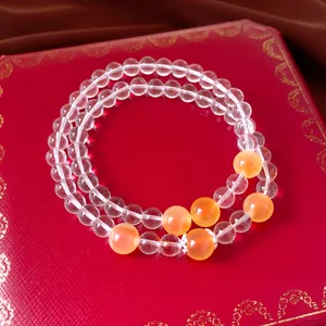Bracelet à trois rangs en quartz clair et agate orange sur un écrin de bijoux rouge élégant