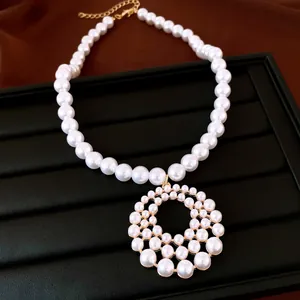 Detailansicht einer eleganten Perlenkette mit einem großen, runden, durchbrochenen Anhänger