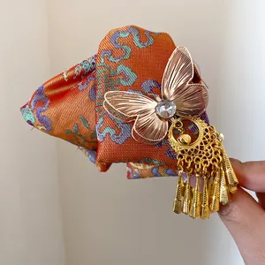 Nahaufnahme einer Haarspange im Ethno-Stil mit orangefarbenem Brokat und goldenem Schmetterling