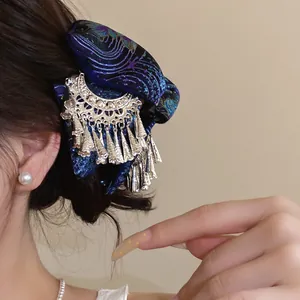 Detailansicht einer vintage Haarspange aus blauem Stoff im Ethno-Stil mit silbernen Quasten.