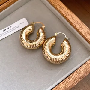 Elegante klobige goldene Creolen mit gerippter Textur in einer stilvollen Schmuckschatulle