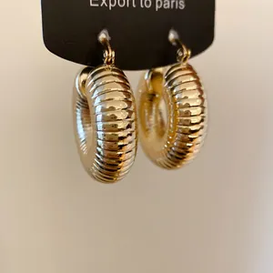 Detailaufnahme der klobigen goldenen Creolen mit gerippter Textur und elegantem Glanz