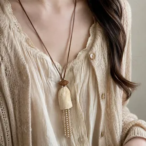 Gros plan d'un collier vintage avec noyau de fruit et gland de perles sur un mannequin.