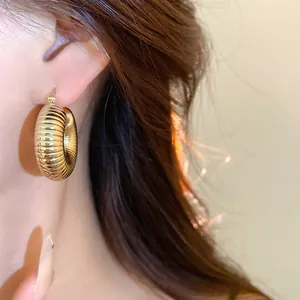 Detailansicht der glänzenden goldenen Creolen mit einem einzigartigen strukturierten Spiralmuster