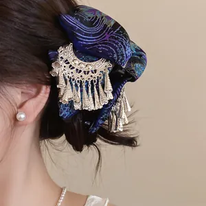 Nahaufnahme einer Vintage-Haarklammer im ethnischen Stil mit blauem Stoff und Quasten