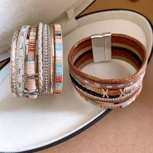 Detailopname van meerlaagse lederen armbanden met magnetische sluitingen en kristallen