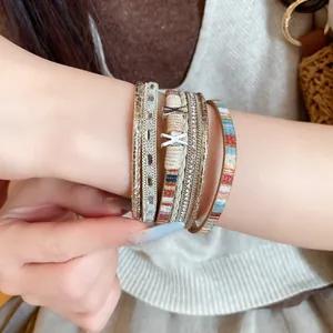 Detailopname van meerlaagse lederen armband met sprankelende strass-steentjes en magneetsluiting