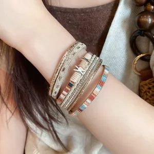 Close-up van een bohemian gelaagde leren armband met strassteentjes en X-vormige accenten.
