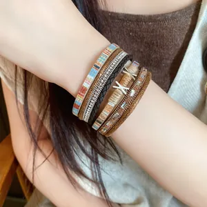 Detailweergave van een boheemse meerlagige leren armband met strassteentjes om een pols