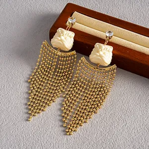 Vue détaillée de boucles d'oreilles à pompons dorés avec tête de lion en résine et zircon