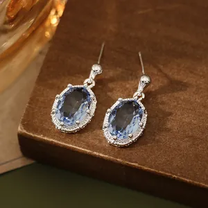 Detailopname van elegante ovale blauwe zirkoon oorbellen met zilveren zetting