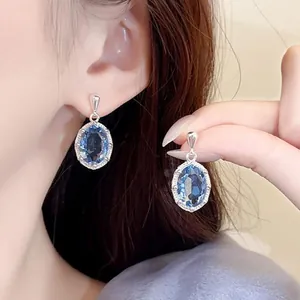 Elegante zilveren drop oorbellen met stralende ovale blauwe zirkonia op een vrouwelijk model
