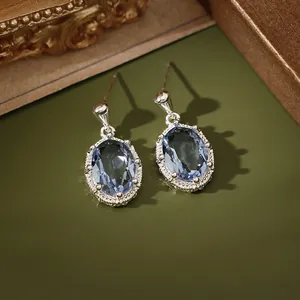 Detailopname van elegante ovale blauwe zirkonia oorknopjes met zilveren vintage zetting