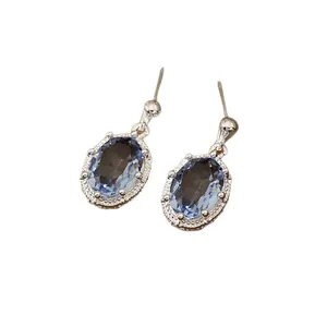 Elegante zilveren naald oorbellen met ovale blauwe zirkoon en sprankelende halo-stenen decor