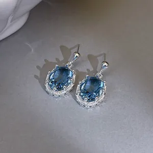 Detailopname van elegante ovale zirkoon oorknopjes met blauwe edelstenen en zilver.
