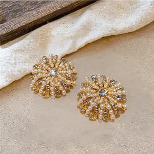 Vue détaillée des boucles d'oreilles fleurs vintage dorées avec perles et cristaux.