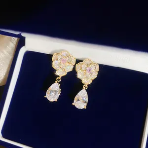 Detailansicht exquisiter Goldblumen-Ohrringe mit rosa Stein und hängendem Tropfen-Zirkon