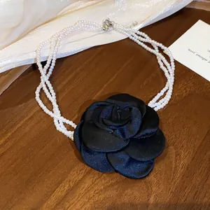 Detailopname van een parelketting met meerdere strengen en een zwarte satijnen bloem