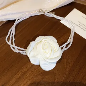 Detail van een vintage satijnen bloem op een meerlaagse parelketting in Franse retrostijl