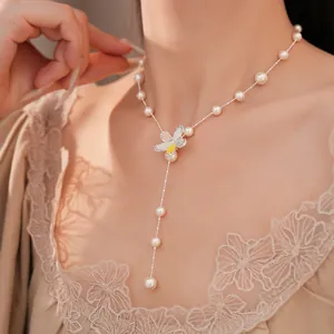 Detailansicht einer eleganten Perlenkette mit Zirkonia-Blumenanhänger an einem Model
