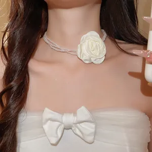 Gedetailleerd beeld van een witte satijnen bloem en parelketting met meerdere lagen.