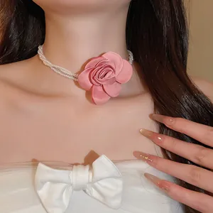Detailopname van de roze satijnen bloem en de dubbellaagse parelketting bij een model