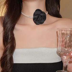 Close-up van een elegante retro choker met een zwarte satijnen bloem en laagjes parels.