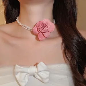 Detail van een vintage meerlaagse parel choker met een grote roze satijnen bloem versiering.