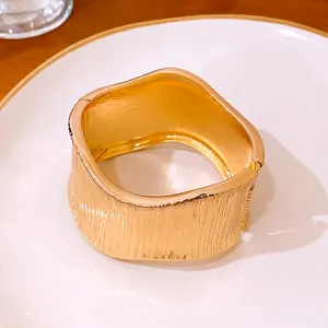 Elegante brazalete dorado texturizado con una forma ovalada irregular y distorsionada