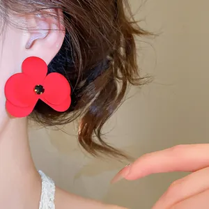 Nahaufnahme eines leuchtend roten Blütenohrrings mit funkelndem schwarzem Strassstein.