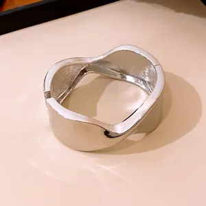 Primer plano de un elegante brazalete ovalado torcido plateado con diseño minimalista