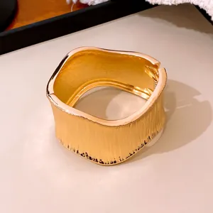 Vista detallada de un brazalete dorado distorsionado con textura vertical elegante